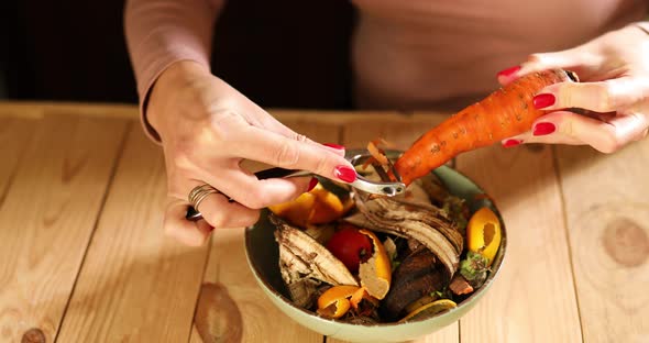 Women scraps peels carrots vegetable peeling, throws in compost bucket, organic composting