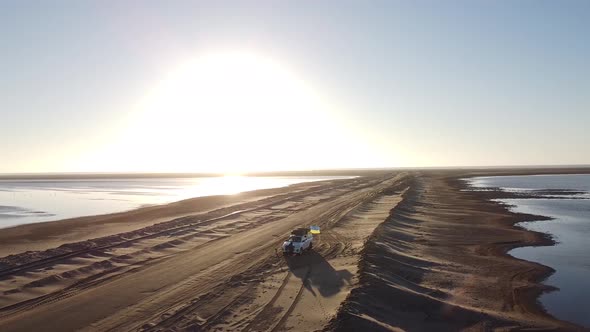 Drone footage of a big white SUV parked on a sandy road near Walvis Bay