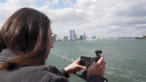 Close Up of Young Woman Taking Videos With Her Smartphone of New York Waterfront From Staten Island