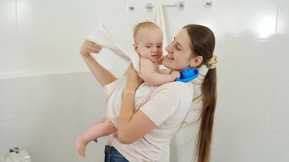 Smiling Mother Taking Her Baby Out of Bath and Wiping with Towel