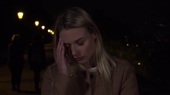 A Young Beautiful Woman Acts Frustrated and Sad in an Urban Area at Night