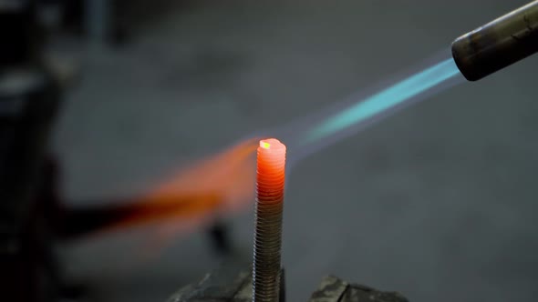 Fire of gas burner heats up red-hot the metal bolt closeup