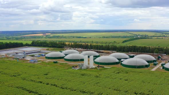 Biogas farm on green fields. Modern agriculture plant in nature. Renewable energy from biomass. 