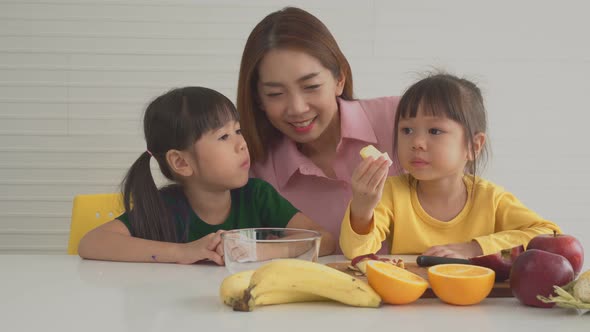 Enjoy Asian mom teaching a little daughter holding knife cut fresh vegetables