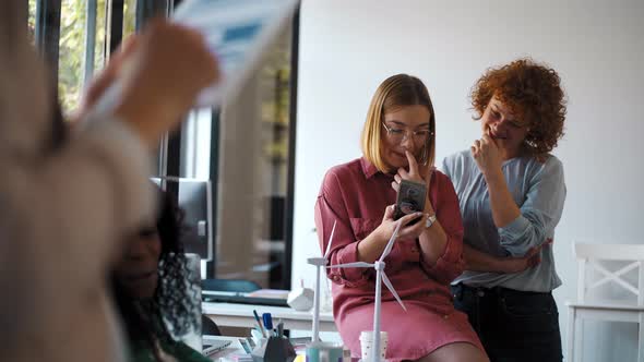 Young woman using smartphone during meeting with wind wheels