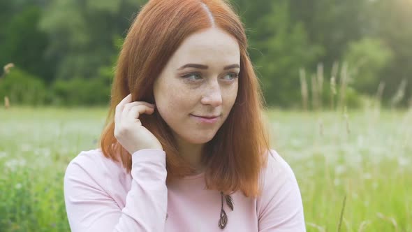 Shy Beautiful Woman Looks Down Up Outdoors in Summer Field, Red Haired Female