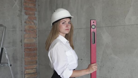 Girl engineer builder at a construction site holds a level in hands.