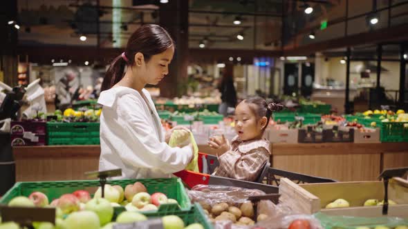 Excited Daughter Helps Mother Put Vegetables Into Bag