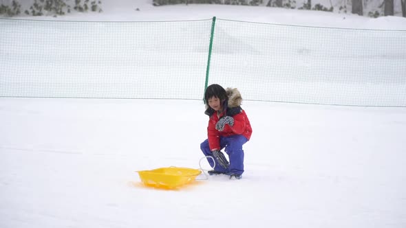 Cute Asian Child Playing Sled On Snow