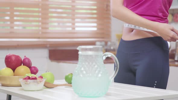 Young female using camera recording when she eating fruits in the kitchen.