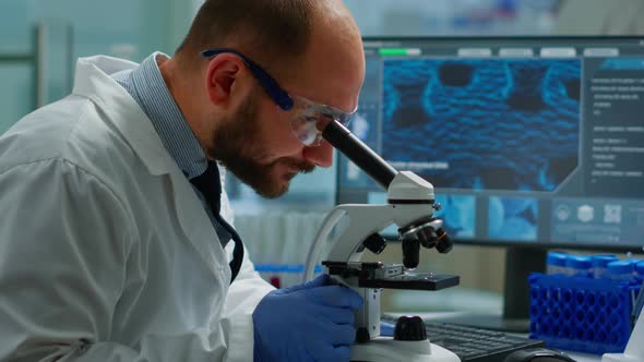 Male Scientist Looking Under Microscope in Medical Development Laboratory