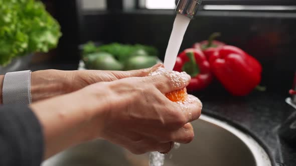 Female Hands are Washing Fresh Orange By Stream of Water