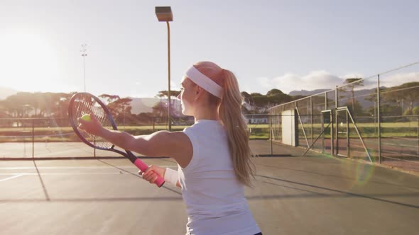 Video of back of caucasian female tennis player holding racket and hitting ball