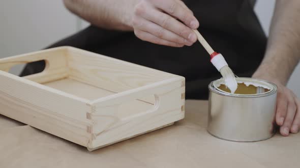 Man Hand Dunks Brush Into Can with White Liquid