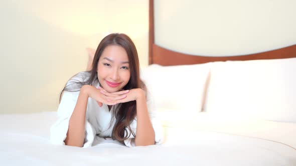 Asian woman relax on bed in bedroom interior