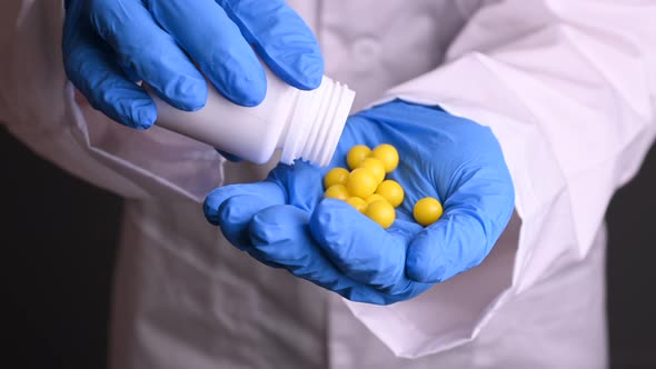 a Doctor in Gloves and a Robe Holds Pills To Treat Diseases. Viruses and Epidemics