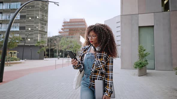 Beautiful African American Woman with Curly Hair Wearing the Shirt and Jeans Hurries Up to the