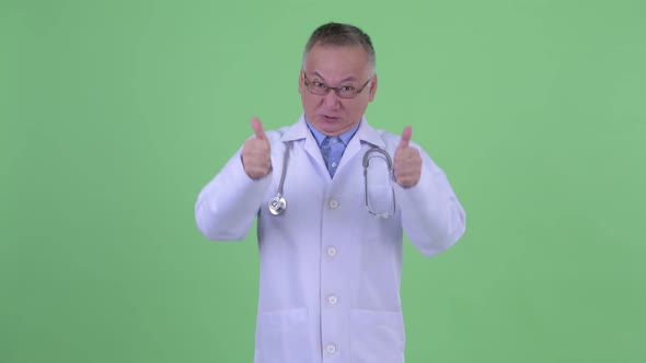 Happy Mature Japanese Man Doctor Giving Thumbs Up and Looking Excited