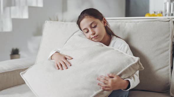 Thoughtful Female Teen Embracing Pillow on Couch