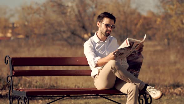 Businessman Relaxing And Reading Fresh Newspaper. Man Sitting On Bench And Reading Newspaper.