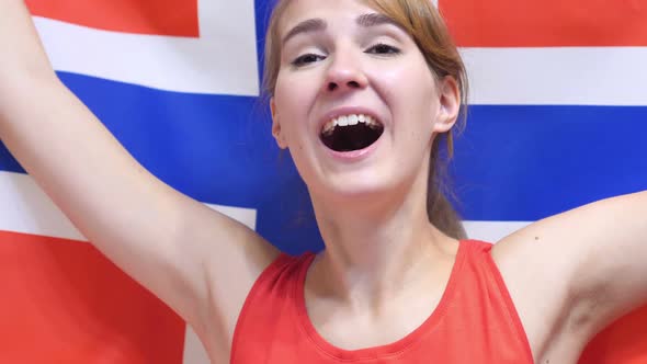 Norwegian Young Woman Celebrating while Holding the Flag of Norway