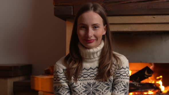 Portrait of a Young Woman Who Looks Into the Camera By the Fireplace at Home