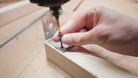 Screwing a Metal Corner to a Wooden Bar with Selftapping Screws Using an Electric Screwdriver