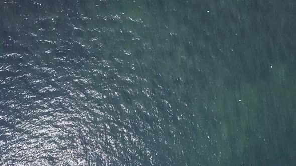 Flying directly over the ocean water off shore in Seaton England. The water is dark and light blue.