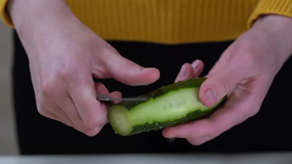 Cleaning a Cucumber with a Knife on a Cutting Board