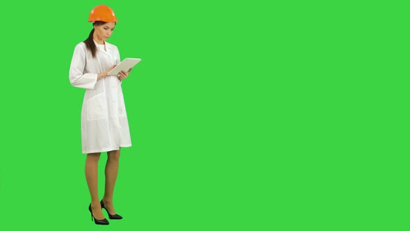 Female Construction Specialist in Hardhat Using Tablet on a Green Screen, Chroma Key