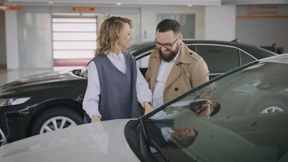 Husband and Wife Choose a New Car in the Showroom of an Official Dealer