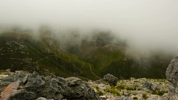 TimeLapse - Mist flowing into valley, shot from rocky vantage point on mountain with hiking trails i