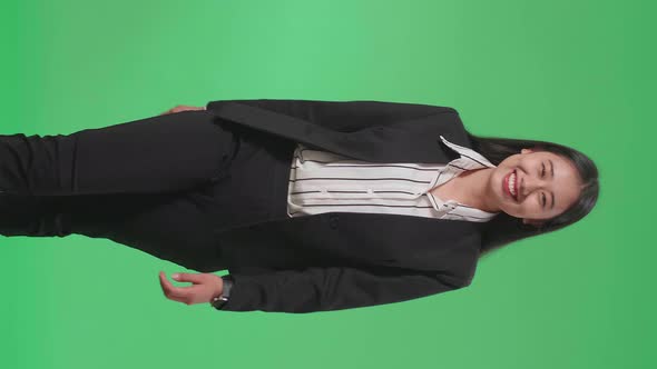 A Smiling Asian Business Woman Walking Through Green Screen In The Studio