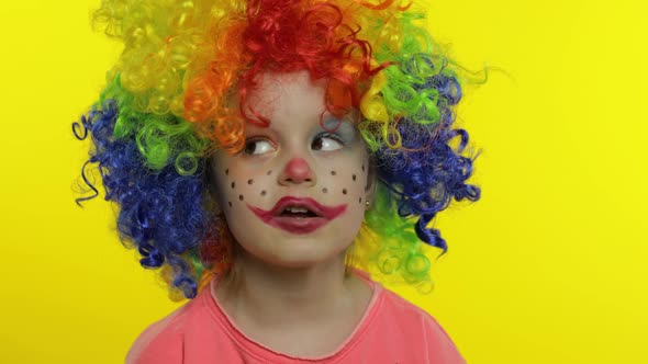 Little Child Girl Clown in Colorful Wig Tells Something Interesting. Having Fun, Smiling. Halloween