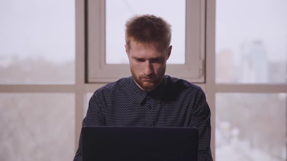 Handsome American Businessman Typing on Laptop in Modern Office