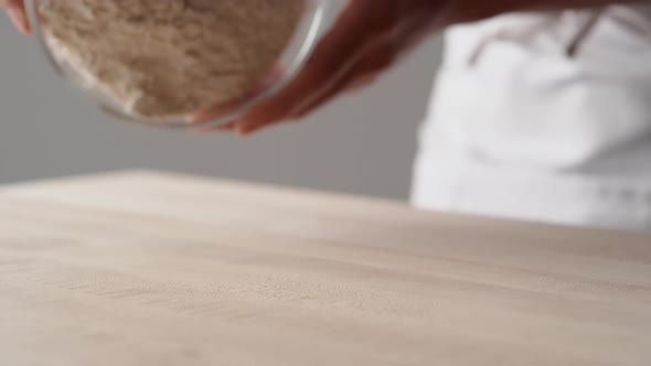 Camera follows hands pouring flour onto a cooking table. Slow Motion.