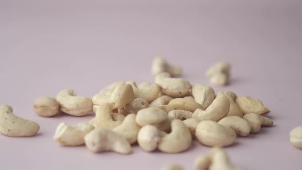 Slow Motion of Cashew Nuts Falling on Light Pink Background