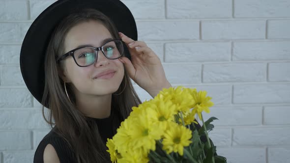 Cute girl in glasses and a hat with yellow flowers.