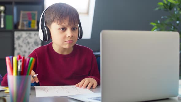 Handheld video of boy with headphones during remote learning at home