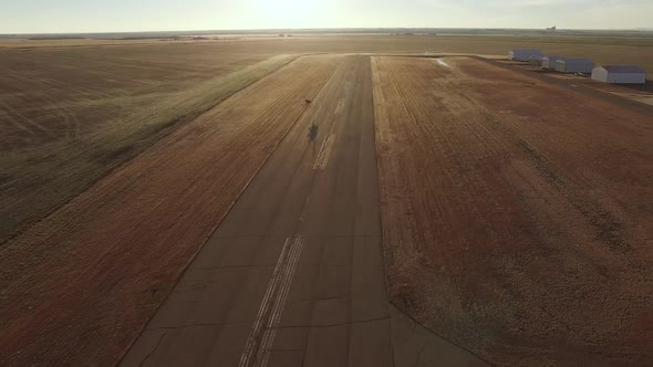 Tilting shot of an air show biplane Pitts S2B flying down the runway at a small airport at sunrise.