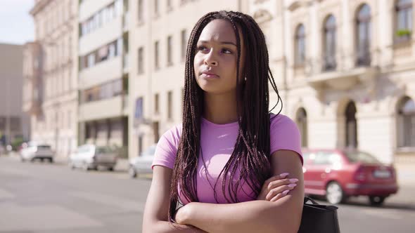 A Young Black Woman Looks Around in the Street in an Urban Area