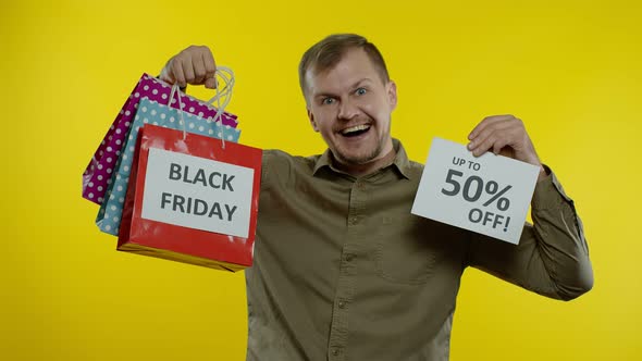 Man Showing Shopping Bags and Up To 50 Percent Off Inscription, Looking Satisfied with Low Prices