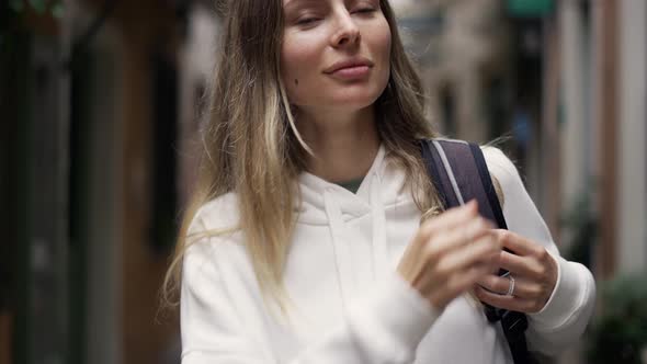 A Girl Tourist at the City Put on Her Backpack on Shoulder