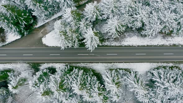 Following a red truck by a drone as top down view from above, driving through a snow covered wintry