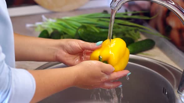 Woman Washing Yellow Pepper in Kitchen