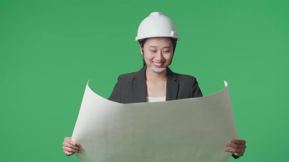 Asian Female Engineer With Looking At Blueprint Then Looking Around While Walking On Green Screen