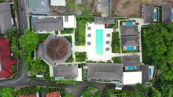 Motorbikes driving by a pool villa complex and construction site in Umalas Bali, aerial top down