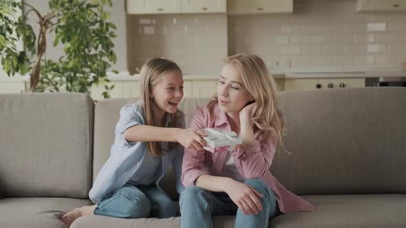 Charming Little Girl is Giving Her Beautiful Young Mom a Present