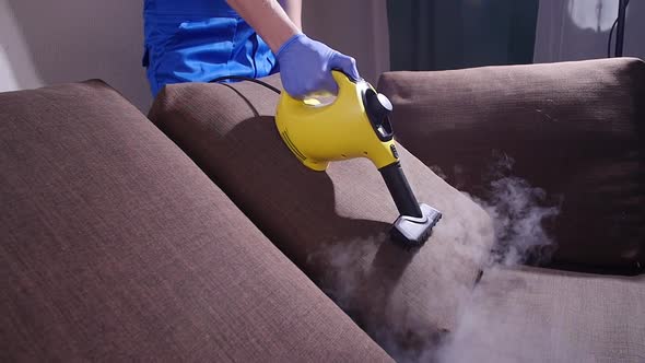 Furniture Cleaning Concept. Cleaning the Sofa with an Antibacterial Steam Cleaner
