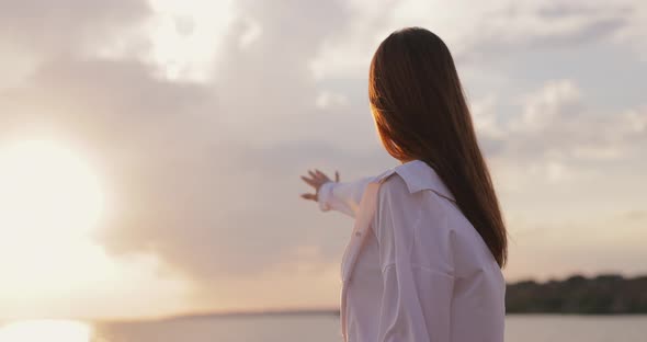 Silhouette of Young Woman Looks at the Sea Sunset From a Hill